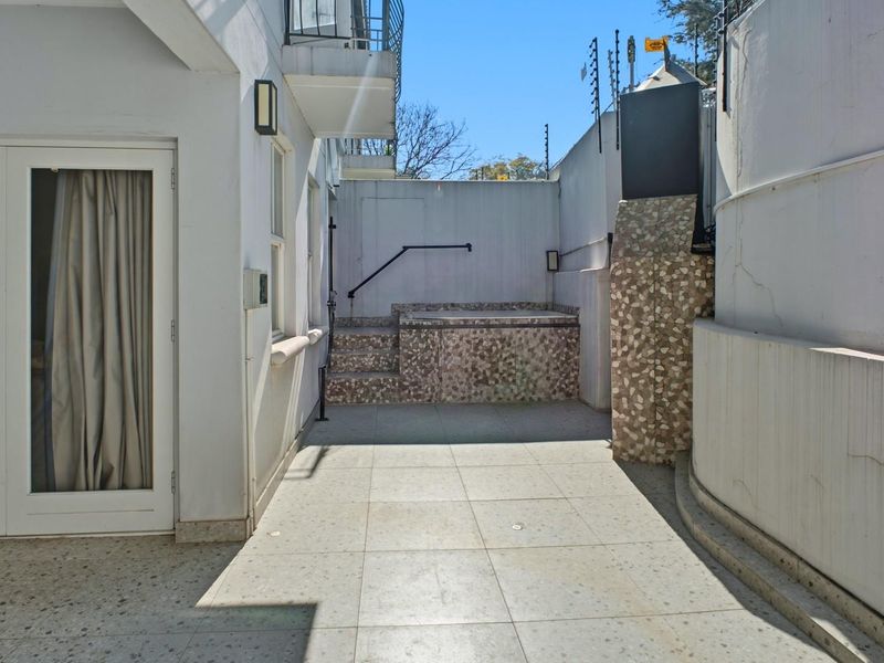 A private outdoor patio area featuring a built-in plunge pool, tiled flooring, and secure perimeter walling with electric fencing.