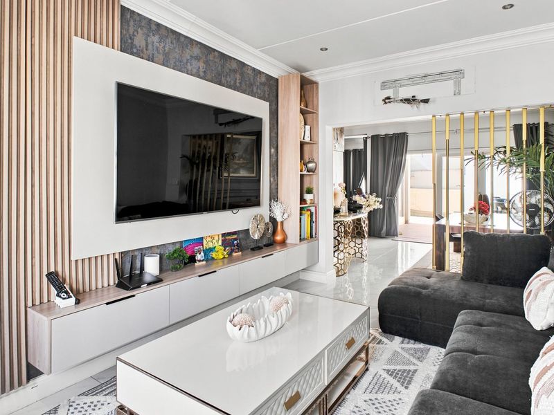 Modern living room featuring a custom built-in media unit with slatted timber accents, tiled flooring, and elegant decorative metal room dividers.