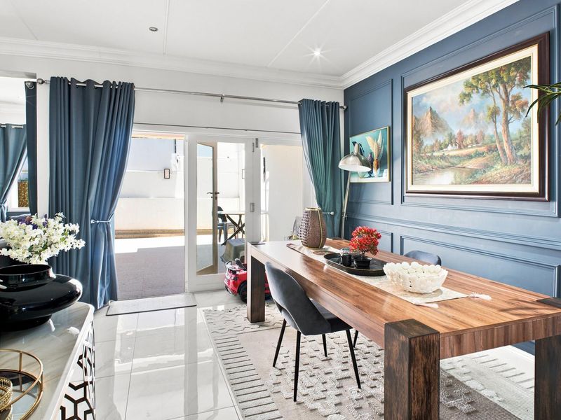 Elegant dining area featuring decorative wainscoting, polished tiled flooring, and direct access to an outdoor patio through double glass doors.