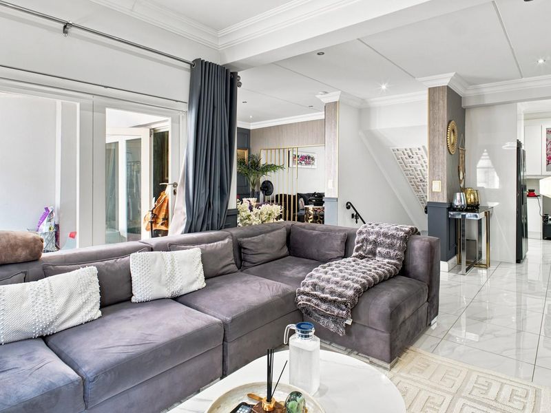 Spacious open-plan living area featuring polished tiled flooring, recessed lighting, and elegant crown molding, seamlessly connecting to the staircase and adjacent kitchen space.