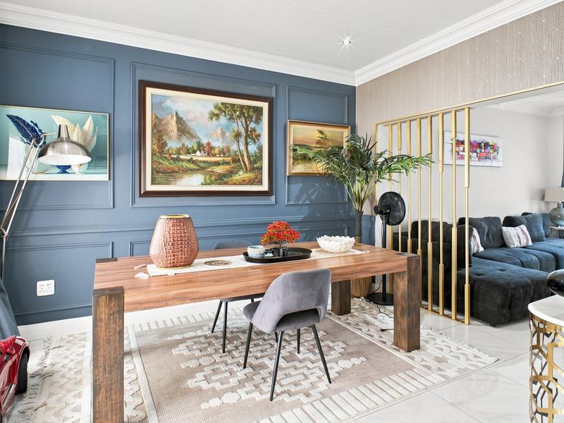 A well-maintained living area featuring elegant blue wainscoting, crown molding, and a modern gold-toned metal room divider separating the space.