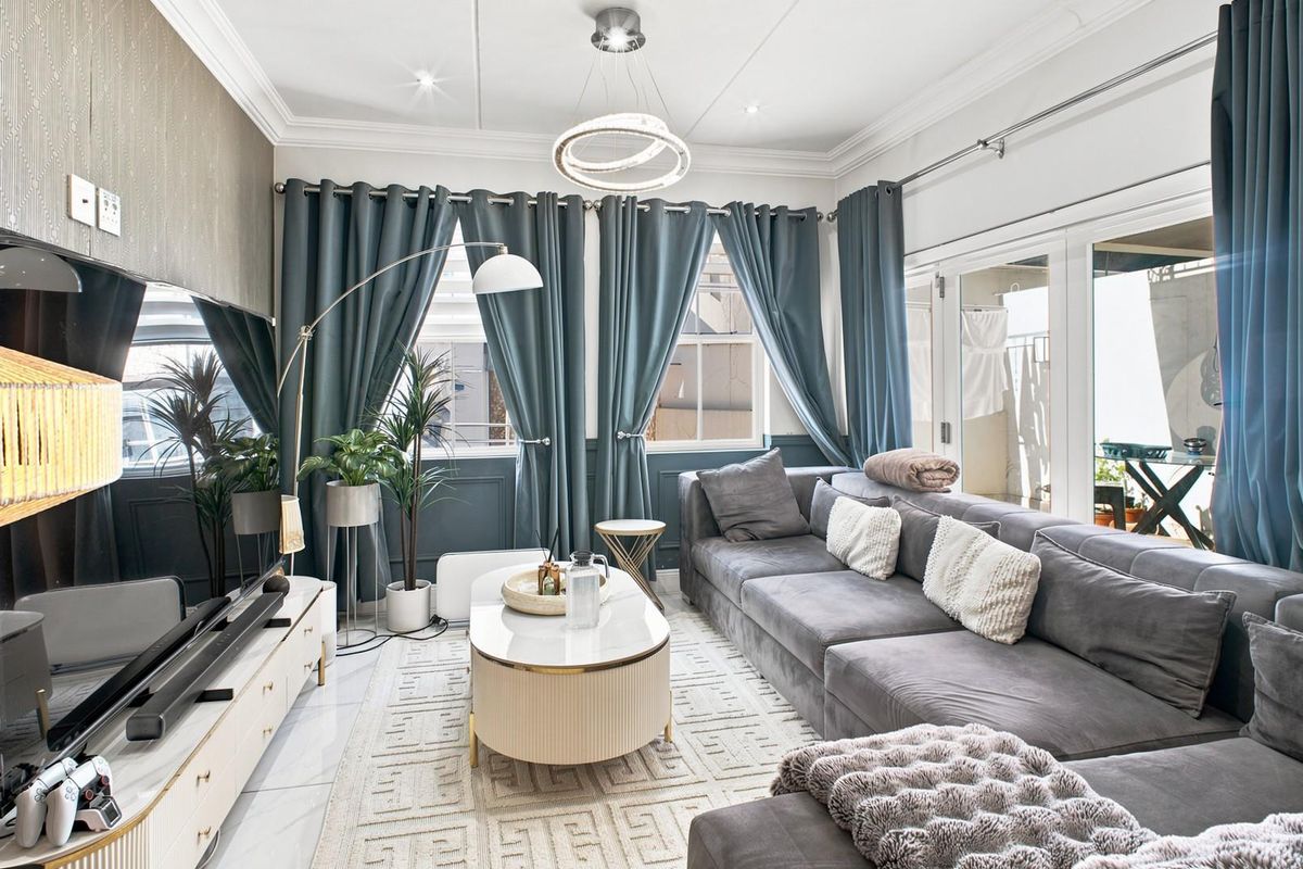 A well-appointed living room featuring elegant wainscoting, crown molding, tiled flooring, and large sliding glass doors that provide access to the outdoor area.