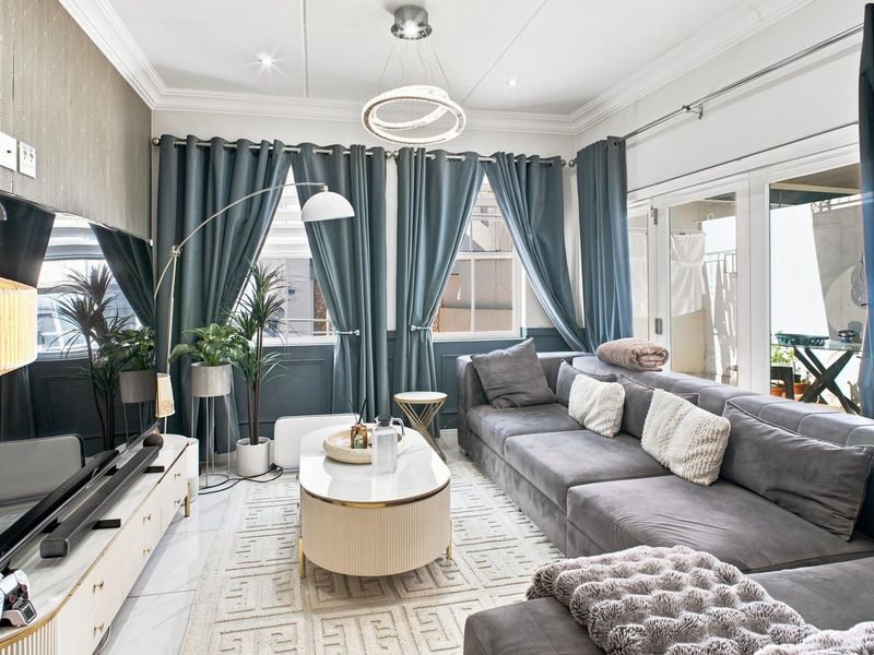 A well-appointed living room featuring elegant wainscoting, crown molding, tiled flooring, and large sliding glass doors that provide access to the outdoor area.