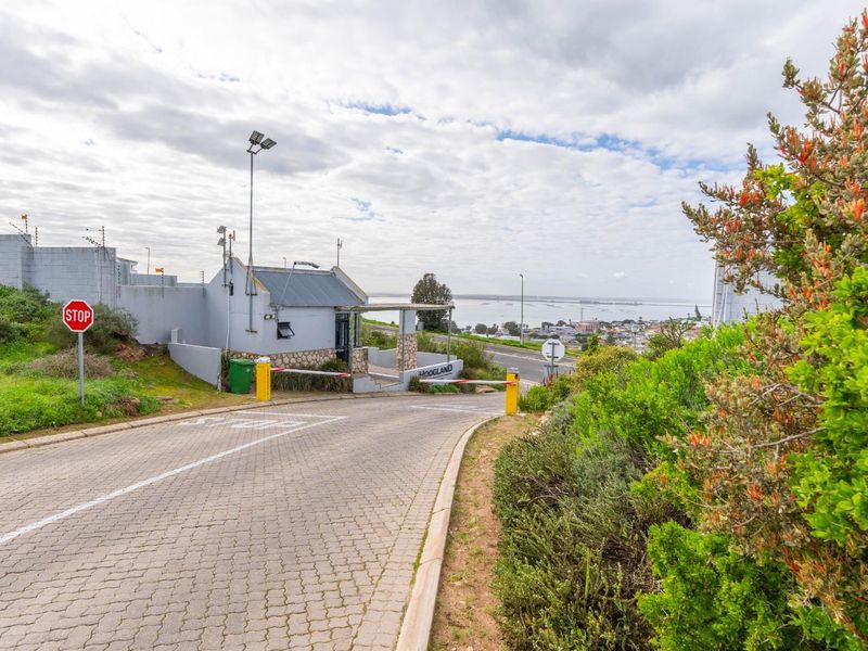 Entrance view of the residential estate featuring a security gatehouse, boom gate access, and paved driveway with perimeter electric fencing.