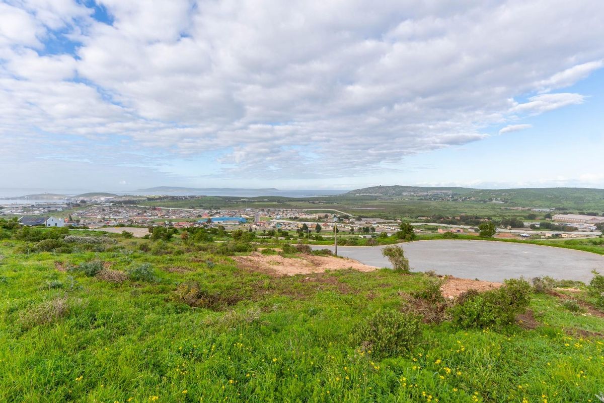 Elevated view overlooking a residential area and coastal landscape from a vacant plot with an existing paved cul-de-sac.