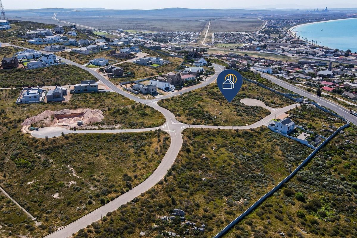 Aerial view of a vacant residential plot situated in a coastal development with established road infrastructure and surrounding neighborhood.