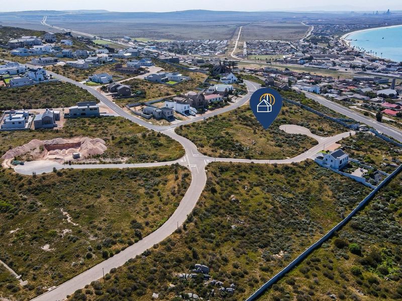 Aerial view of a vacant residential plot situated in a coastal development with established road infrastructure and surrounding neighborhood.