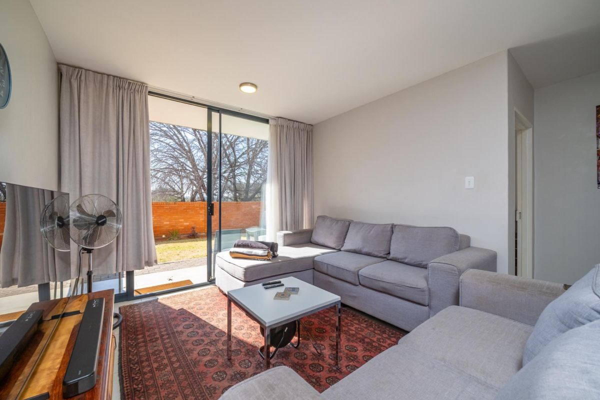 A bright living room featuring large sliding glass doors that provide direct access to an outdoor patio and garden area.