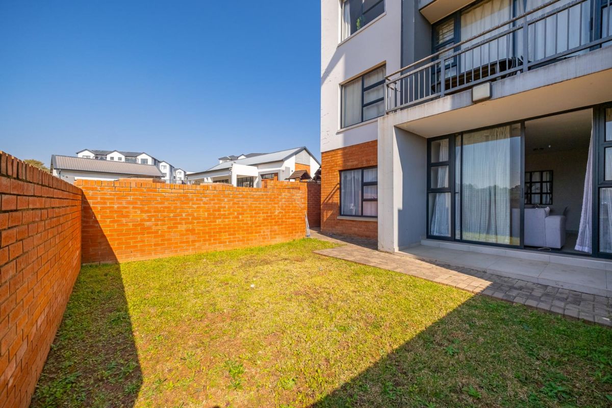 Private rear garden featuring a brick boundary wall, paved patio area, and direct access to the apartment via sliding glass doors.