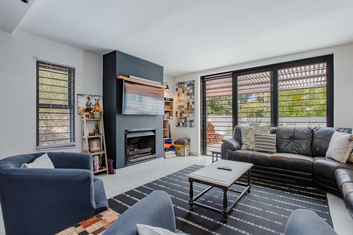 A bright living room featuring a modern fireplace, tiled flooring, and large sliding glass doors that provide access to an outdoor area.