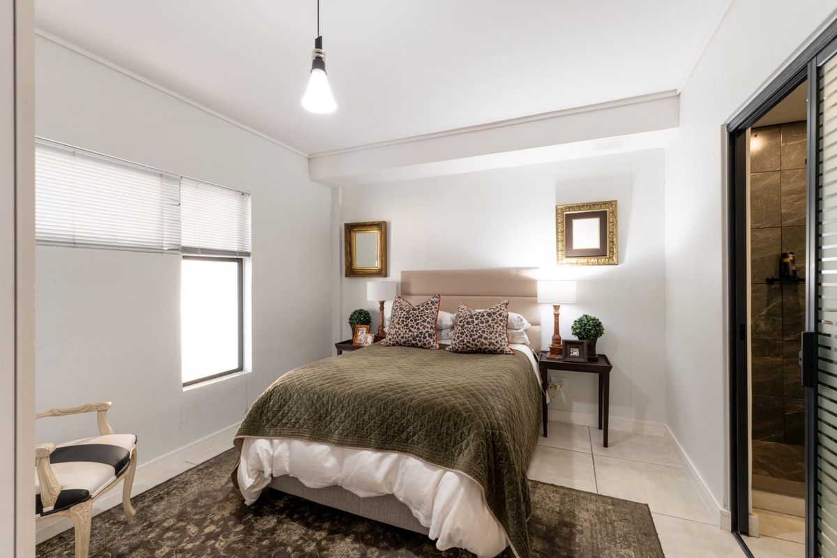 A well-maintained bedroom featuring tiled flooring, neutral walls, and direct access to an en-suite bathroom.