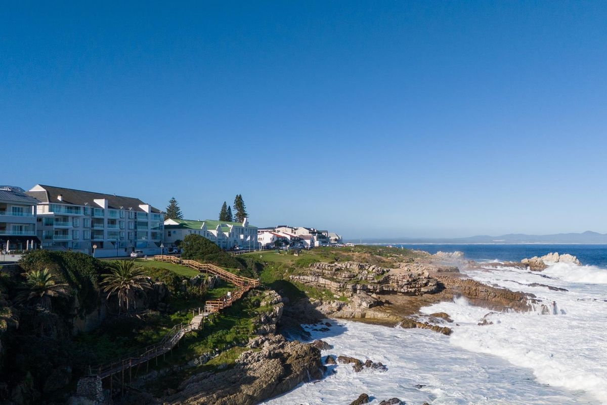 Aerial view of the coastal penthouse location, showcasing the cliffside landscape, pedestrian boardwalk, and proximity to the ocean.