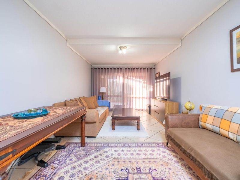 A comfortable living room featuring tiled flooring, a coved ceiling, and a large sliding glass door that provides natural light.