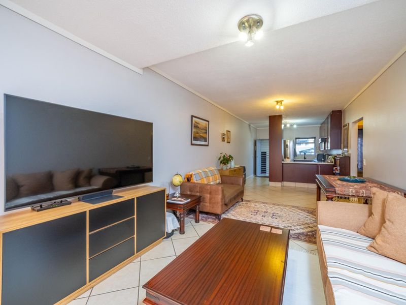 Open-plan living and kitchen area featuring tiled flooring and functional kitchen cabinetry, providing a versatile space for daily living and dining.