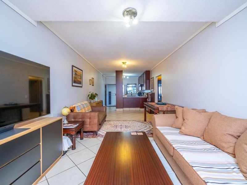 Open-plan living and dining area featuring tiled flooring and a connected kitchen space with built-in cabinetry.