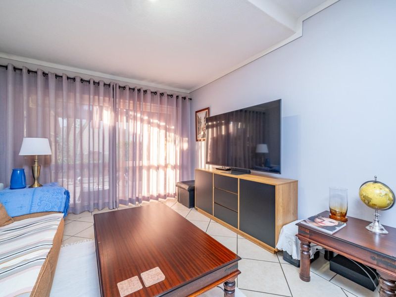 A comfortable living room featuring tiled flooring and a large sliding glass door that provides access to the outdoor area.