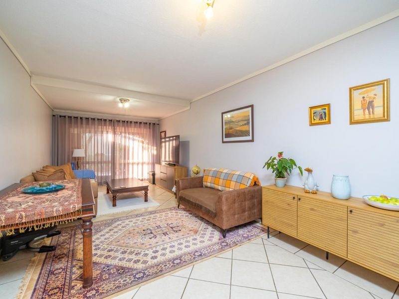 A spacious living room featuring tiled flooring and a large sliding glass door that provides access to the outdoor area.