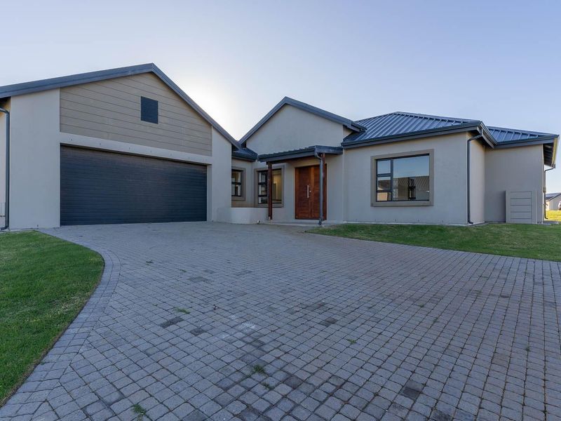 Modern single-story residential home featuring a paved driveway, double garage, and a well-maintained front lawn.