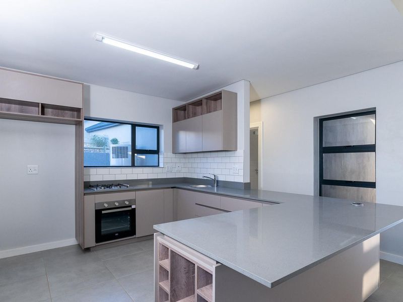 Modern kitchen featuring sleek cabinetry, stone countertops, subway tile backsplash, built-in oven, gas hob, and a functional breakfast bar island.