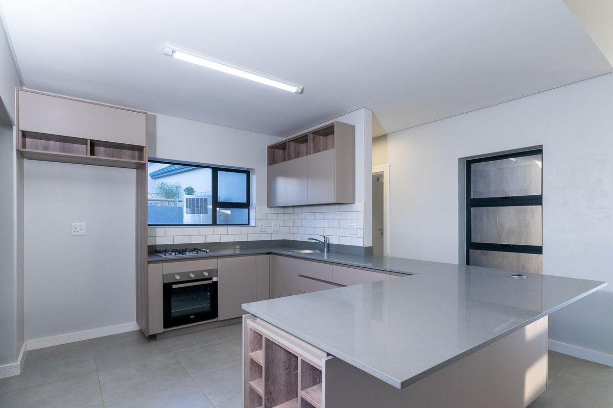 Modern kitchen featuring sleek cabinetry, stone countertops, subway tile backsplash, built-in oven, gas hob, and a functional breakfast bar island.