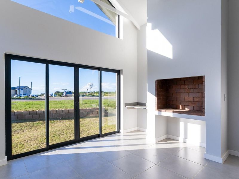 Bright, modern living area featuring a built-in brick fireplace, high vaulted ceilings, and large sliding glass doors opening to the exterior.
