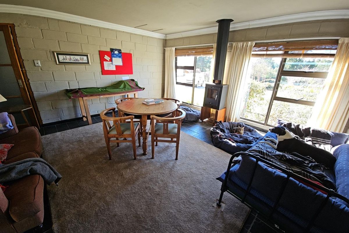 Spacious living room featuring exposed blockwork walls, tiled flooring, and a freestanding fireplace, offering a rustic aesthetic with ample natural light.