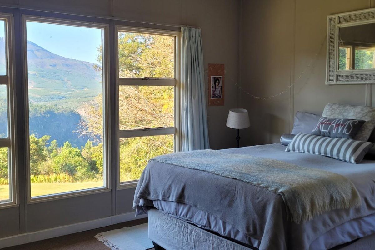 A cozy bedroom featuring large windows that offer expansive mountain and forest views, providing a bright and serene atmosphere.