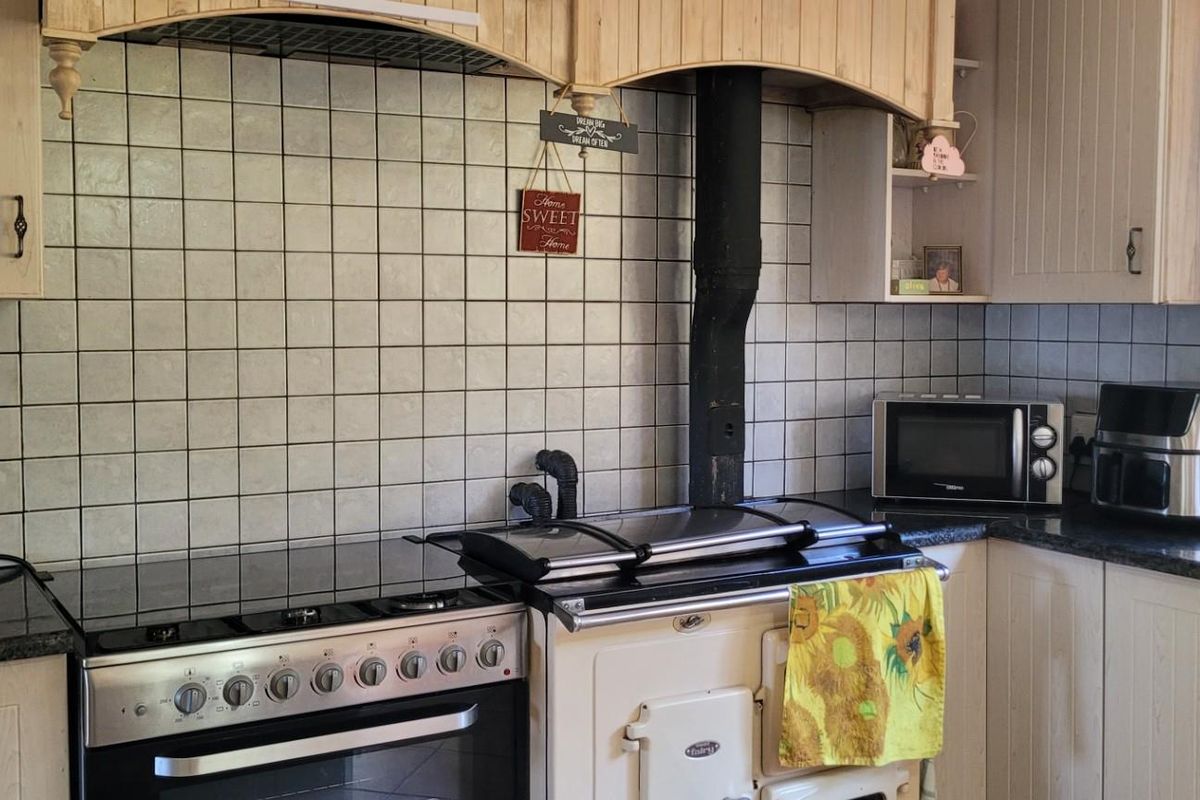 A functional kitchen featuring traditional cabinetry, a tiled backsplash, and a dual-stove setup including a classic range cooker.
