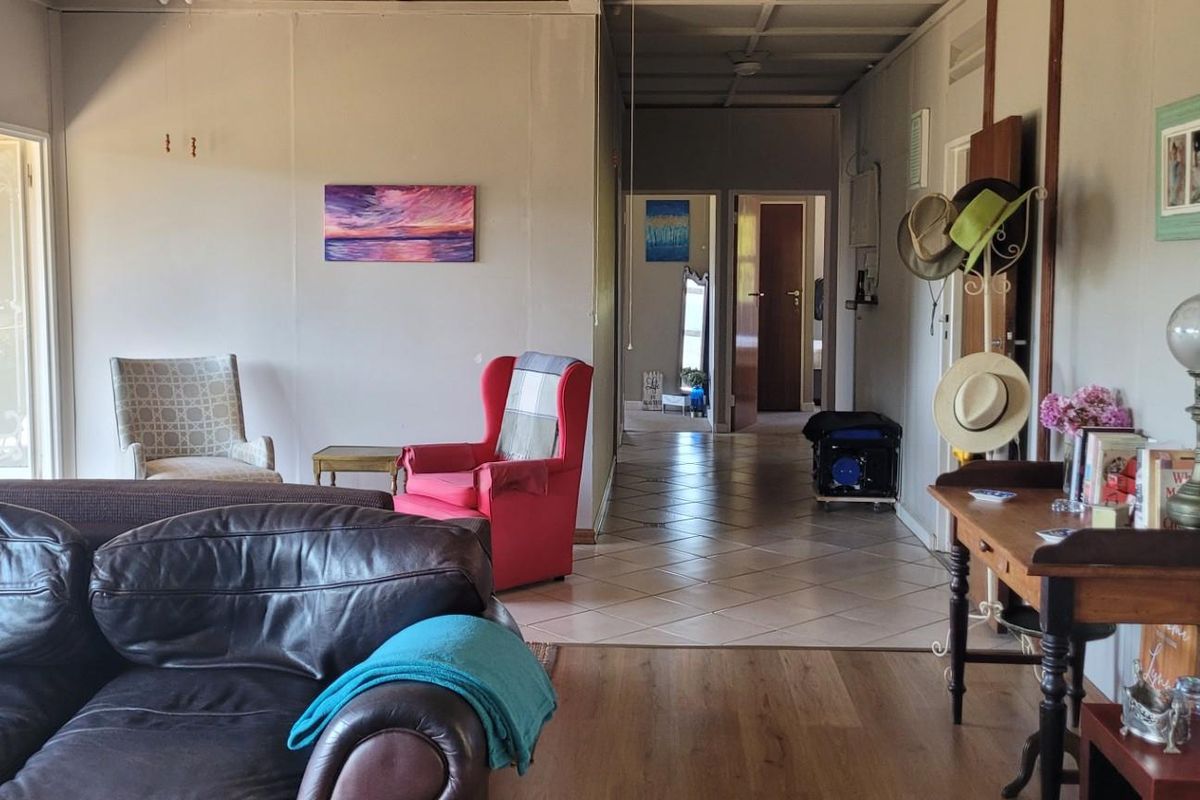 A living room area featuring a mix of timber and tiled flooring, with a sliding glass door providing access to the exterior.