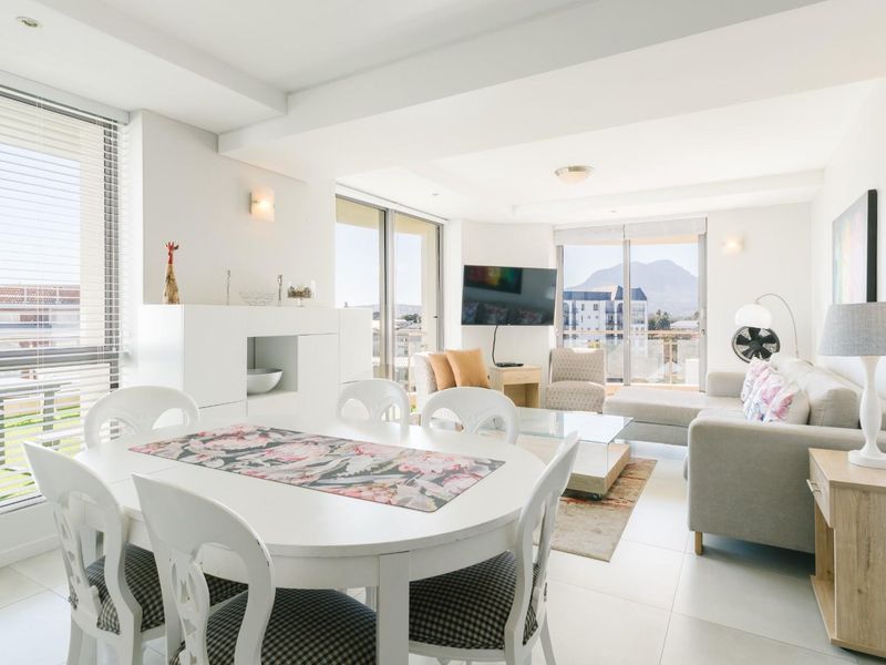 Bright and spacious open-plan living and dining area featuring tiled floors, large sliding glass doors, and abundant natural light with mountain views.