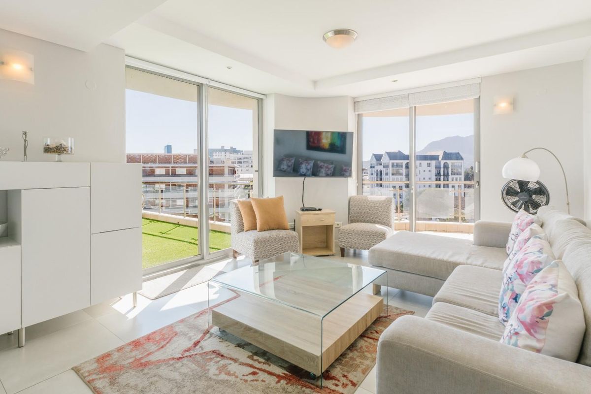 Bright and airy living room featuring large sliding glass doors that open onto a balcony, providing ample natural light and urban views.