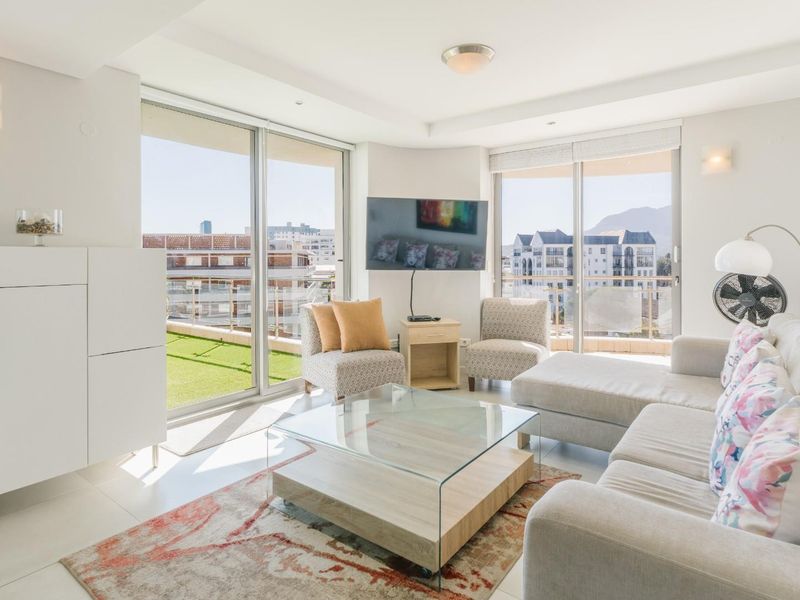 Bright and airy living room featuring large sliding glass doors that open onto a balcony, providing ample natural light and urban views.