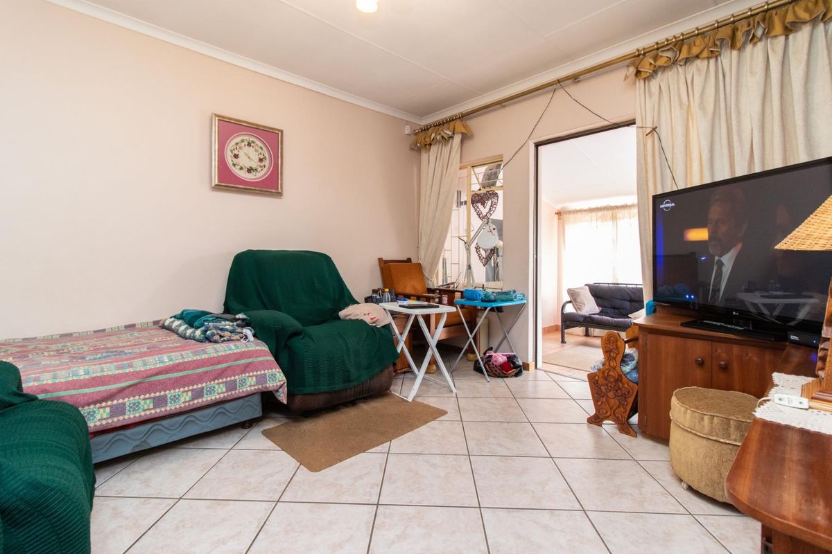 A living room featuring tiled flooring and an open doorway leading to an adjacent space, providing a functional layout with neutral wall finishes.