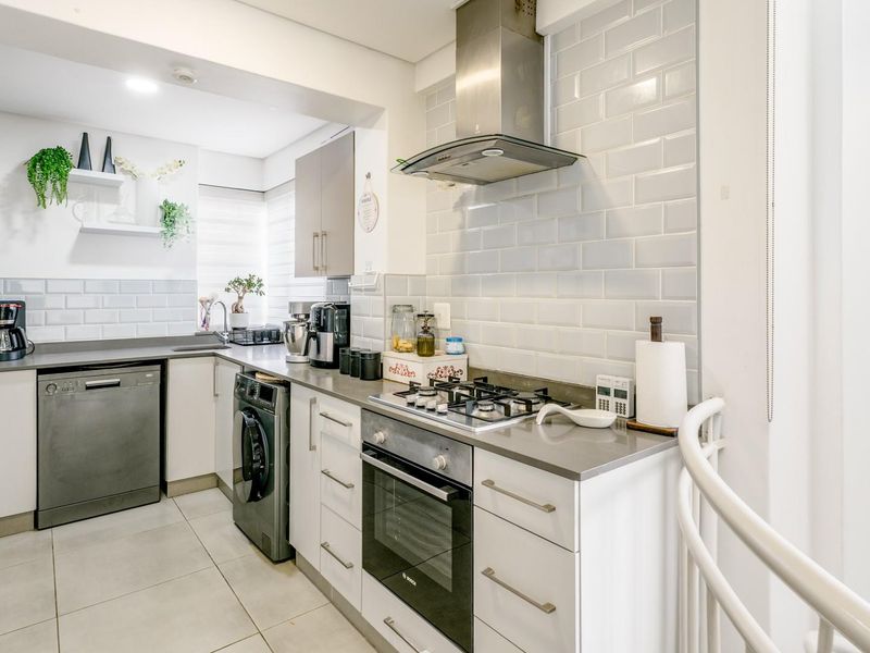 Modern kitchen featuring subway tile backsplash, stone countertops, gas hob, built-in oven, and integrated cabinetry with a clean, functional layout.