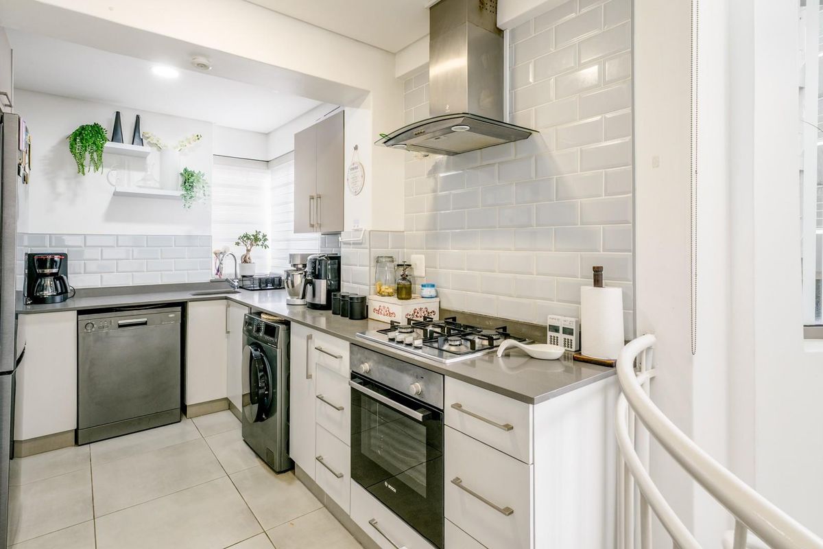 Modern kitchen featuring subway tile backsplash, stone countertops, gas hob, built-in oven, and integrated cabinetry with a clean, functional layout.