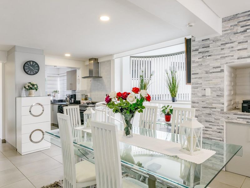 Bright open-plan living and dining area featuring a stone veneer accent wall, recessed lighting, and a modern kitchen with built-in cabinetry.