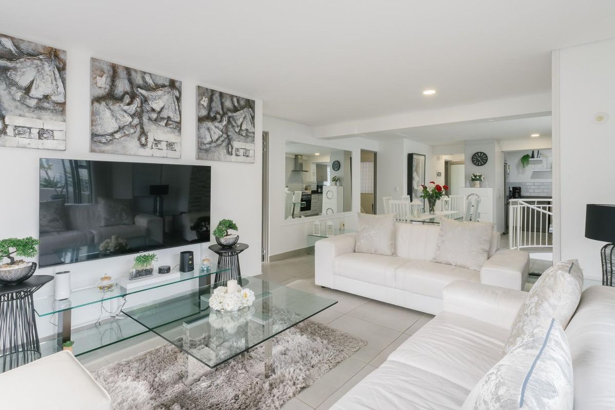 Bright and spacious open-plan living area featuring neutral tiled flooring, recessed lighting, and a functional layout connecting to the kitchen and dining space.