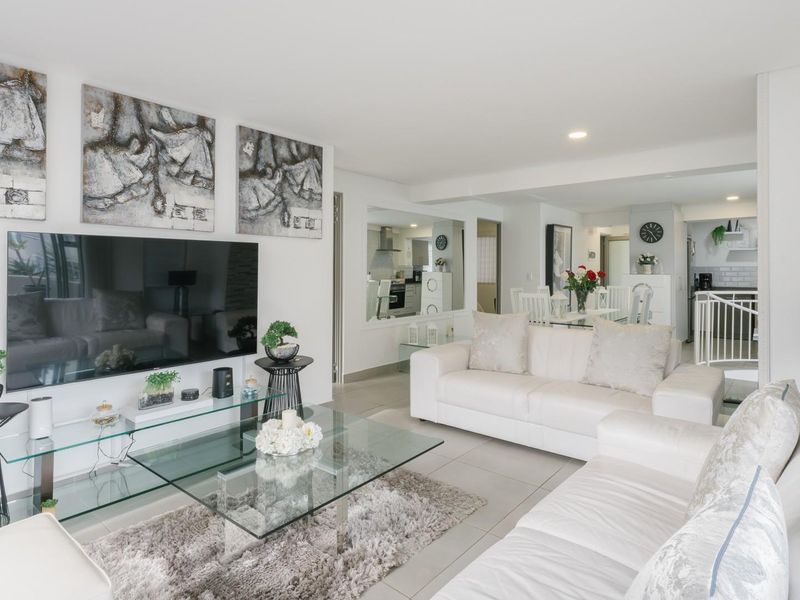 Bright and spacious open-plan living area featuring neutral tiled flooring, recessed lighting, and a functional layout connecting to the kitchen and dining space.