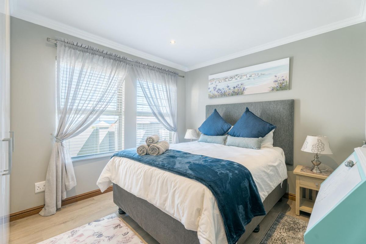 A well-maintained bedroom featuring light laminate flooring, recessed downlighting, and neutral wall tones, creating a bright and comfortable living space.