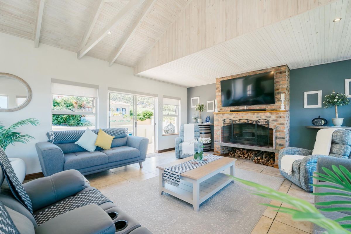 Spacious living room featuring a vaulted timber ceiling, exposed brick fireplace, and large sliding doors providing natural light and access to the outdoors.