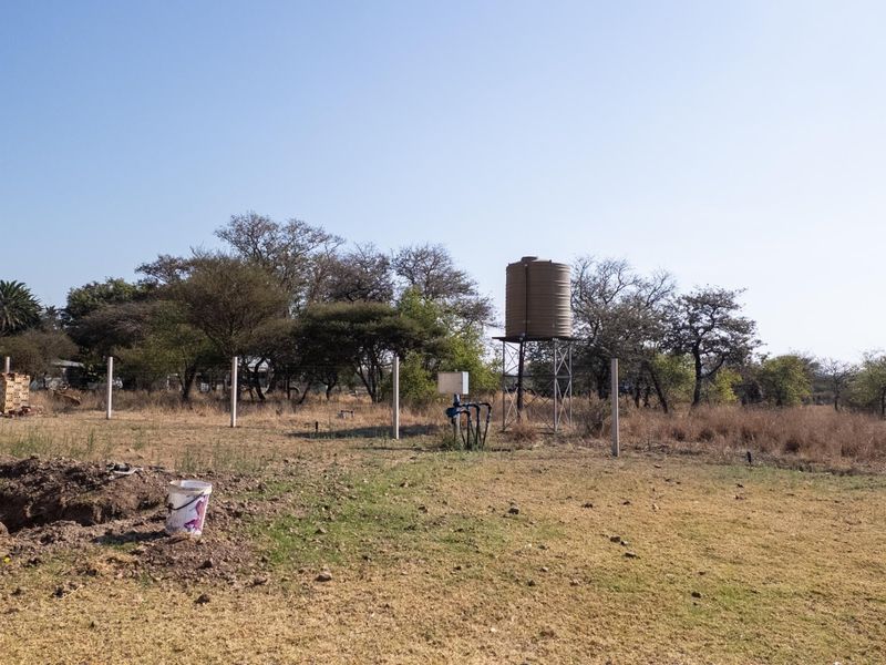 Open farm land featuring a raised water storage tank, borehole pump infrastructure, and perimeter fencing on the property grounds.