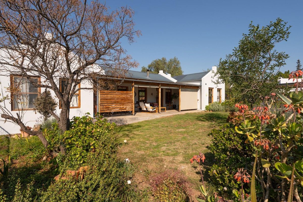 Rear view of the house featuring a covered patio area, timber privacy screen, and a well-maintained garden setting.