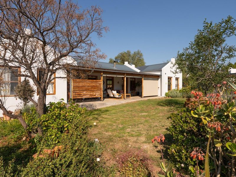 Rear view of the house featuring a covered patio area, timber privacy screen, and a well-maintained garden setting.