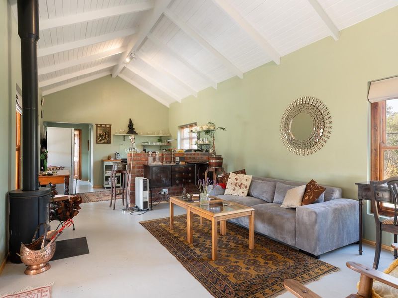 Spacious open-plan living area featuring a vaulted ceiling with exposed beams, a central brick partition, and a freestanding wood-burning fireplace.