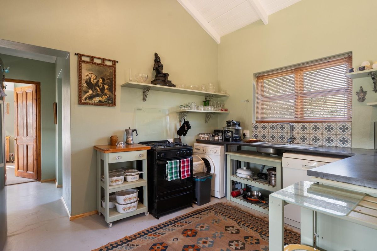 A functional kitchen featuring a gas stove, tiled backsplash, stainless steel sink, and open shelving under a vaulted ceiling.