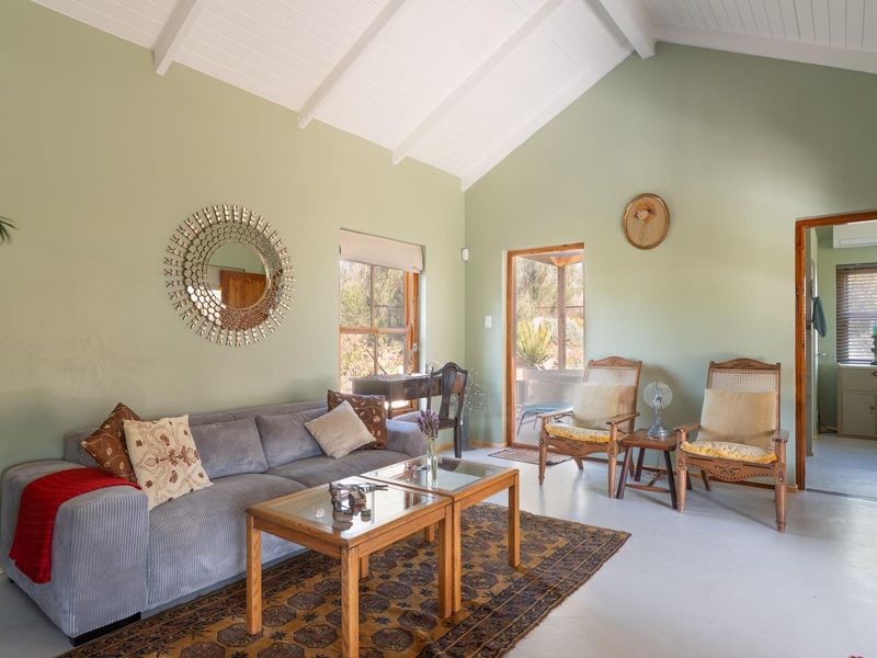 A spacious living room featuring a high vaulted ceiling with exposed beams, painted concrete floors, and direct access to an outdoor patio area.