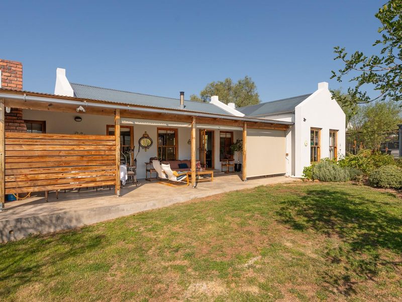 A well-maintained rear exterior featuring a spacious covered patio with timber pergola, concrete flooring, and direct access to the garden.