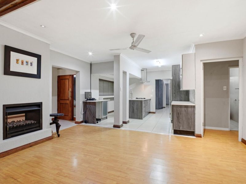 Spacious open-plan living area featuring a built-in fireplace, laminate flooring, and a modern kitchen with integrated cabinetry and functional workspace.