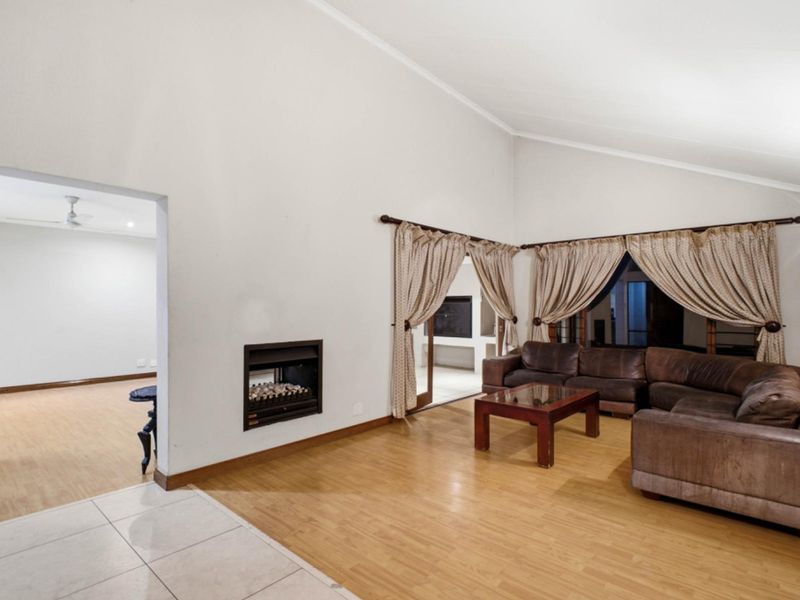 Spacious living room featuring a vaulted ceiling, built-in fireplace, and a combination of laminate and tiled flooring with access to an adjacent room.