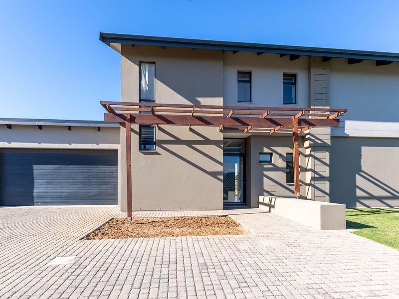 Modern front elevation featuring a paved driveway, double garage, and a prominent timber pergola over the entrance area.